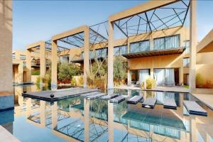 un edificio con una piscina con sillas delante en Duplex Moderne 233m2 dans une magnifique résidence, en Marrakech