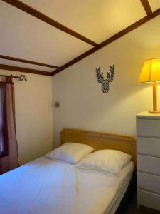 a bedroom with a bed with a lamp and a antlers on the wall at Pyrénées 2000 chalet 4 pers. in Bolquere Pyrenees 2000