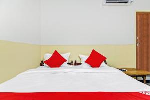 un letto bianco con cuscini rossi sopra di OYO Suraj Residency a Warangal