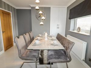 a dining room with a table and leather chairs at 20 Glasfryn Avenue in Prestatyn