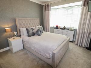 a bedroom with a large white bed and a window at 20 Glasfryn Avenue in Prestatyn