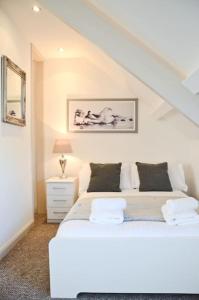a white bedroom with a white bed and a staircase at Modern Attic Studio Apartment with harbour views in Penzance