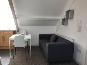 a living room with a couch and a table at Modern Attic Studio Apartment with harbour views in Penzance