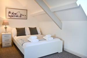 a bedroom with a white bed with two towels at Modern Attic Studio Apartment with harbour views in Penzance