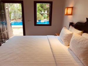 a bedroom with a large white bed with a window at NeakBong Residence in Siem Reap