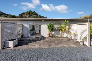 une maison blanche avec des plantes devant elle dans l'établissement Hidden Away - Tauranga Bay Holiday Unit, à Mahinepua