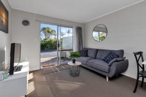 a living room with a couch and a tv at Hidden Away - Tauranga Bay Holiday Unit in Mahinepua