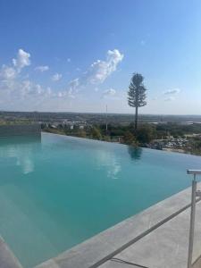 a large blue swimming pool with a tree in the background at Luxe Cityscape @ Waterfall Ellipse in Midrand