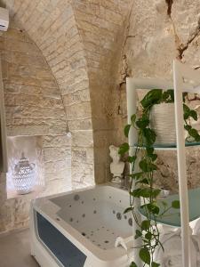 un bagno in pietra con una pianta e una vasca. di GB Grotta Bianca a Ostuni