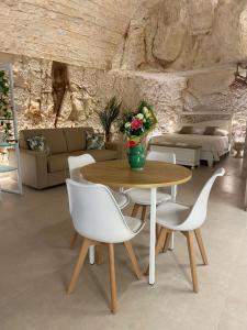 un soggiorno con tavolo in legno e sedie bianche di GB Grotta Bianca a Ostuni