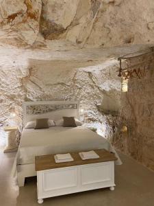 una camera con un letto bianco su un muro di pietra di GB Grotta Bianca a Ostuni