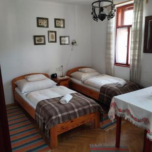 a room with two beds and two tables and a window at Karádi Vendégház in Háromhuta