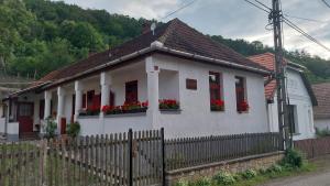 a white house with red windows and a fence at Karádi Vendégház in Háromhuta