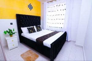a bedroom with a large bed with a black headboard at First class apartments in Kiambu