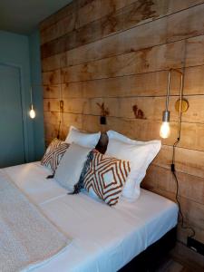 a bedroom with a wooden wall and a bed with pillows at MyDeer - Deluxe rooms & shared kitchen in Malmedy