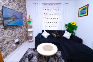 a living room with a black couch and a table at First class apartments in Kiambu +3 photos