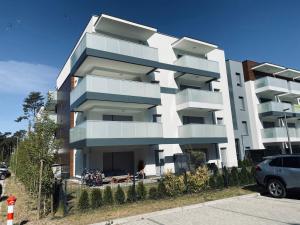 Apartament Amilado في بوغورزيلكا: مبنى أبيض فيه سيارة متوقفة أمامه