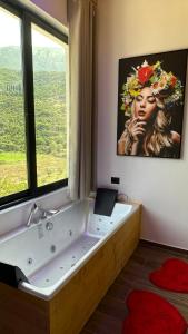 een badkamer met een groot bad en een groot raam bij Hotel Nemercka in Përmet