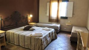 a hotel room with two beds and a window at Baglio Dello Zingaro in Scopello
