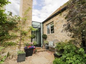 a stone house with a courtyard and plants at The Grain Store in Witney