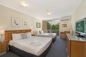 
a hotel room with two beds and a television at Quality Inn Airport Heritage in Brisbane
