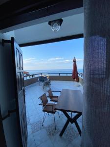 a table and chairs on a balcony with a view of the ocean at Karaoulanis Beach in Agios Ioannis Pelio