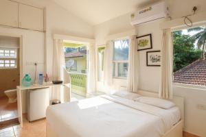 a bedroom with a large white bed and windows at Casa Legend Economy, Calangute Goa in Candolim