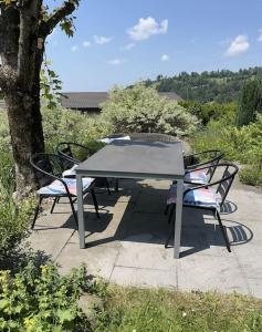 a picnic table with two chairs sitting next to a tree at Charming alps apartment perfect for walk/cycle/ski in Eschenbach