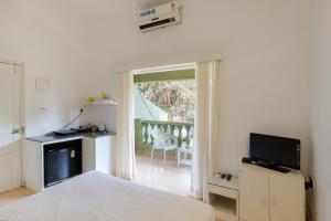 a bedroom with a bed and a television and a balcony at Casa Legend Economy, Calangute Goa in Candolim