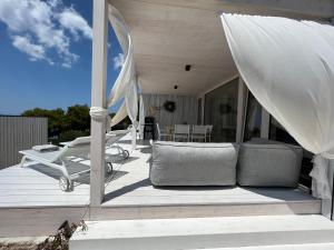 a wooden deck with a couch and chairs on it at BUQEZ ECO RESORT - Beach Villas 2 and 8 - Seaview, new wifi! in Drage