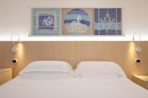 a bedroom with two beds and pictures on the wall at Hotel Corte Rosada in Porto Conte