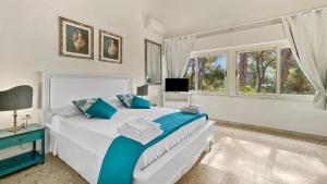 a white bedroom with a bed and a television at Villa Susy al mare in La Maddalena