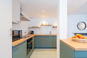 a kitchen with blue cabinets and a bowl of fruit at Appartement Meuse & Mono, en hyper centre in Charleville-Mézières +6 photos
