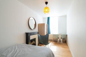 a bedroom with a bed and a mirror and a chair at Appartement Meuse & Mono, en hyper centre in Charleville-Mézières