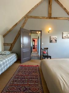 a bedroom with two beds and a door with a rug at Le gîte du Quai aux Gîtes de Cormenin in Saint-Hilaire-sur-Puiseaux