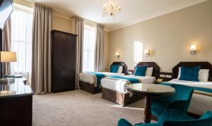 a hotel room with three beds and a chandelier at Harcourt Hotel in Dublin