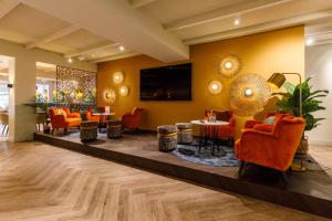 una hall con sedie arancioni e tavoli in un edificio di Hotel Restaurant Piccard a Vlissingen