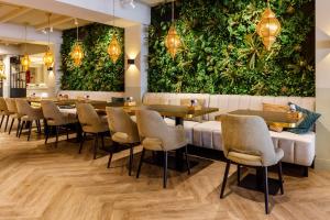 een restaurant met tafels en stoelen en een muur van planten bij Hotel Restaurant Piccard in Vlissingen