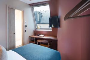 a bedroom with a bed and a desk with a window at Hôtel Maxim Quartier Latin in Paris