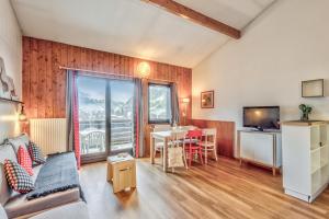 a living room with a table and a tv at Résidence Pierre & Vacances La Rivière in Chamonix