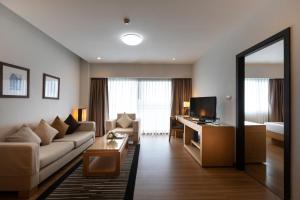 a living room with a couch and a desk with a television at Kantary Hotel Kabinburi in Kabin Buri