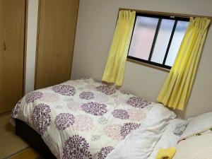 um quarto com uma cama e uma janela com cortinas amarelas em IM guest house em Osaka