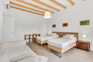 Habitación con 2 camas, paredes blancas y techos de madera. en Alessia's Flat- Naviglio Grande en Buccinasco