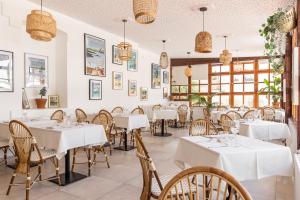 una sala da pranzo con tavoli e sedie bianchi di Villa Sainte Anne a Porquerolles