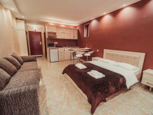 a bedroom with a bed and a couch and a kitchen at APART HOTEL ORBI in Batumi