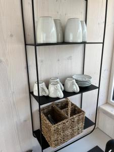 a shelf with dishes and bowls and a basket at BUQEZ ECO RESORT - Beach Villas 2 and 8 - Seaview, new wifi! in Drage