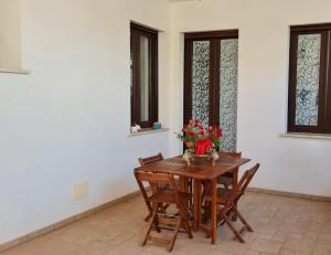 a wooden table with chairs and a vase of flowers on it at Dasylirion Vacanze in Cursi
