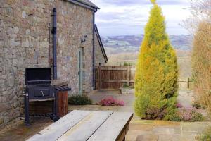 a stone building with a wooden bench and a stove at Rhiwddu Barns in Llangadog