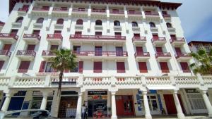 a large white building with red doors and windows at Hendaye plage, Résidence Eskualduna A in Hendaye