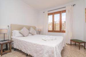 um quarto branco com uma cama branca e uma janela em Ca'n Torronet em Port d'Alcudia